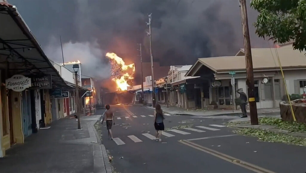 The sky is thick with smoke and flames engulf the air as wildfires rage through Front Street in downtown Lahaina, Maui. Image: Alan Dickar via AP.